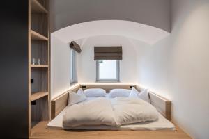 a bedroom with a white bed with a window at Alpin & Stylehotel Die Sonne in Parcines