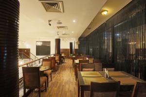 uma sala de jantar com mesas e cadeiras de madeira em Hotel Arch Plaza - Near Delhi Airport em Nova Deli
