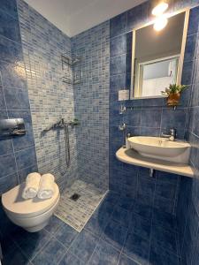 a blue tiled bathroom with a toilet and a sink at Stella in the Village Junior Studio Sea View II in Plakias