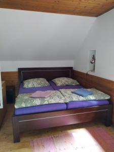 1 cama con sábanas y almohadas moradas en una habitación en Chata Sedmidomí, en Lučany nad Nisou