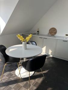 una mesa blanca con sillas y un jarrón de flores. en Designer apartment, en Charlottenlund