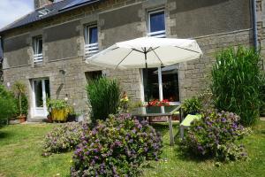 a table with an umbrella in front of a house at Chambre d'hôtes Kerioret Izella in Kerlaz