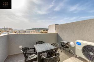 un patio con tavolo e sedie sul balcone. di A sunny 2BR Pent with comfy, fully equipped living by 360 Estates a San Pawl il-Baħar