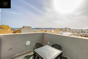 un tavolo e sedie su un balcone con vista di A sunny 2BR Pent with comfy, fully equipped living by 360 Estates a San Pawl il-Baħar
