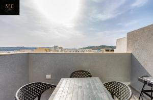 un tavolo e sedie su un balcone con vista di A sunny 2BR Pent with comfy, fully equipped living by 360 Estates a San Pawl il-Baħar
