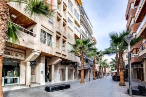a street with palm trees in front of a building at Canonigo Torres in Torrevieja