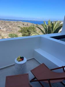 un balcón con 2 sillas y un bol de fruta en Acanthus Oia - Suites With Private Hot Tub, en Oia
