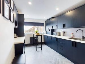 Luxurious 3 bedroom Flat في ليفربول: مطبخ مع دواليب زرقاء داكنة ومغسلة