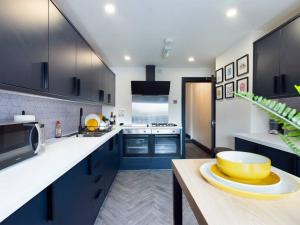 Luxurious 3 bedroom Flat في ليفربول: مطبخ مع خزائن زرقاء ووعاء أصفر على منضدة