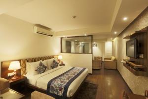 um quarto de hotel com uma cama e uma televisão em Hotel Arch Plaza - Near Delhi Airport em Nova Deli