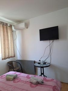 a bedroom with a bed and a tv on the wall at Hoste Pikante in Pančevo