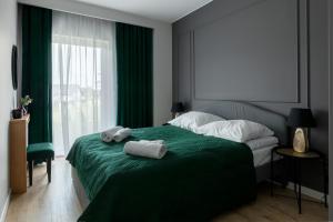 a bedroom with a green bed with towels on it at Apartament Radosny in Kudowa-Zdrój