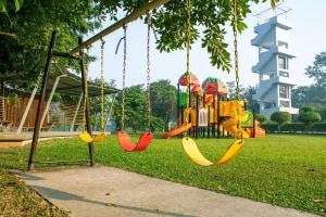 Dream Square Resort في Gazipur: ملعب مع مراجيح ملونة في الحديقة