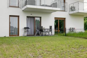 ein weißes Haus mit einer Terrasse und einem Rasenhof in der Unterkunft Apartament Radosny in Kudowa-Zdrój