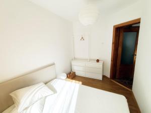 a white bedroom with a bed and a wooden floor at Apartament 14 in Băile Herculane