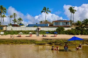 a group of people in the water at a beach at Pousada a Capela in Arembepe