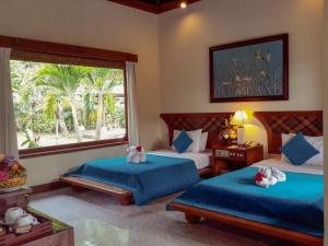 a bedroom with two beds and a large window at Puri Bagus Candidasa in Candidasa