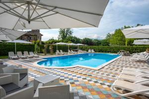 a swimming pool with umbrellas and lounge chairs at B&B Villa Corte Degli Dei in Lucca