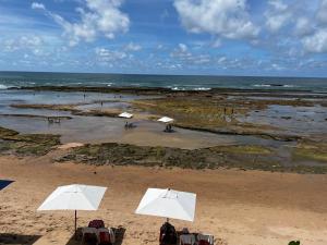 dos sombrillas blancas en una playa con el océano en Pousada a Capela, en Arembepe