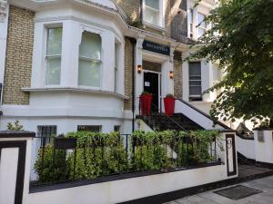 una casa blanca con una valla delante en NOX Olympia, en Londres