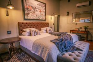 Schlafzimmer mit einem Bett, einem Tisch und einem Spiegel in der Unterkunft Okapuka Safari Lodge in Windhoek