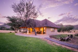 een klein huis met een rieten dak in een veld bij Okapuka Safari Lodge in Windhoek