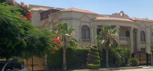 a large house with palm trees in front of it at Super luxurious villa with large landscape areas in Cairo