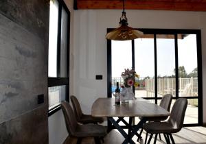 ein Esszimmer mit einem Tisch, Stühlen und Fenstern in der Unterkunft Gilboa Siesta / סייסטה בגלבוע in Nurit