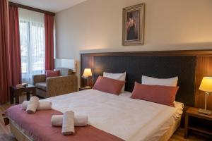ヴェリングラードにあるАпартамент и Студия "Спа Вълшебство"の大きなベッドと椅子が備わるホテルルームです。