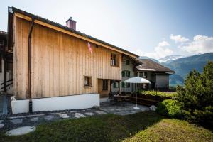 ein großes Holzgebäude mit einem Tisch und einem Sonnenschirm in der Unterkunft Ferienhaus Chalet Steckli in Brienz
