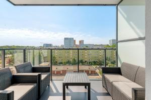 a balcony with couches and a table and a view at Downtown Apartments Seaside Baltea Park & Parking in Gdańsk