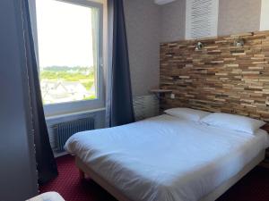 a bedroom with a bed and a large window at Hotel Restaurant Le Phare in Perros-Guirec