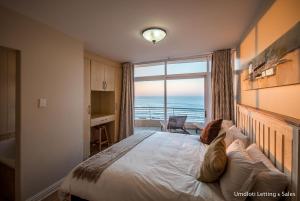 a bedroom with a large bed with a view of the ocean at 5A Sugar Beach with Inverter in Umdloti