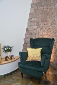 einem grünen Stuhl mit gelbem Kissen neben einer Ziegelwand in der Unterkunft Traditional Villa Relax in Zefiría