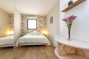 a bedroom with two beds and a table with flowers at Le Cri de la Chouette - Appt avec terrasse in La Chapelle-Thouarault