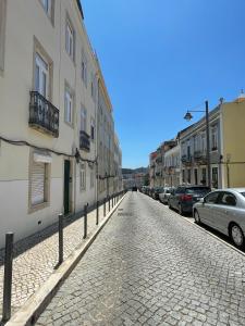 una calle adoquinada con coches aparcados en una ciudad en BELEM PLACE - free parking area en Lisboa