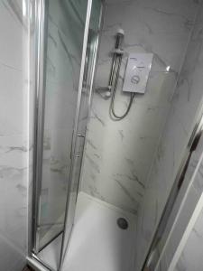a shower stall with a glass door with a shower at Cosy studio flat In teddington in Teddington