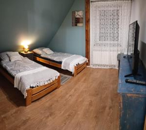 a bedroom with two beds and a television in it at Świerkowe Siedlisko pokoje gościnne in Węgorzewo