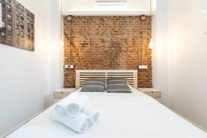 een slaapkamer met een wit bed en een bakstenen muur bij Apartamento 1hab con estilo cerca de Ventas in Madrid