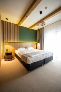 a bedroom with a large bed and a green wall at Stokker Hotel in Oradea