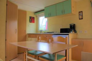 una cocina con mesa y sillas. en CAMPING VERT LAVANDE, en Belmont-sur-Rance