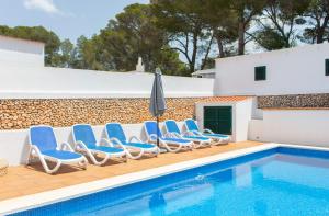 uma piscina com cadeiras e um guarda-sol ao lado de uma casa em Villa Xaloc em Cala Galdana