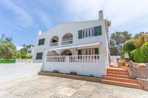 uma casa branca com uma escada em frente em Villa Xaloc em Cala Galdana