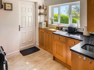 a kitchen with wooden cabinets and a window at Little Saxby in Crowborough