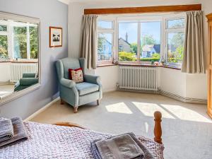 a bedroom with a bed and a chair and windows at Little Saxby in Crowborough