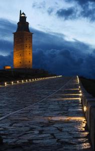 een vuurtoren met lichten ervoor 's nachts bij Apartamento Breogan Coruña in A Coruña