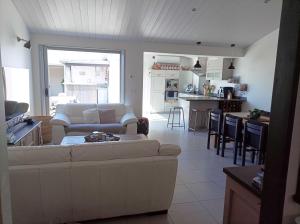 a living room with a white couch and a kitchen at Villa des Moineaux in Sainte-Marie-de-Ré