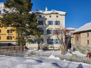 Ein weißes Gebäude mit einem Zaun im Schnee in der Unterkunft Palazzo in Bivio