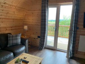 uma sala de estar com um sofá e uma varanda em Pond View Pod 3 With Private Hot Tub - Pet Friendly -Fife - Loch Leven - Lomond Hills em Kelty