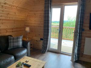 a living room with a couch and a balcony at Pond View Pod 3 With Private Hot Tub -Fife - Loch Leven - Lomond Hills in Kelty